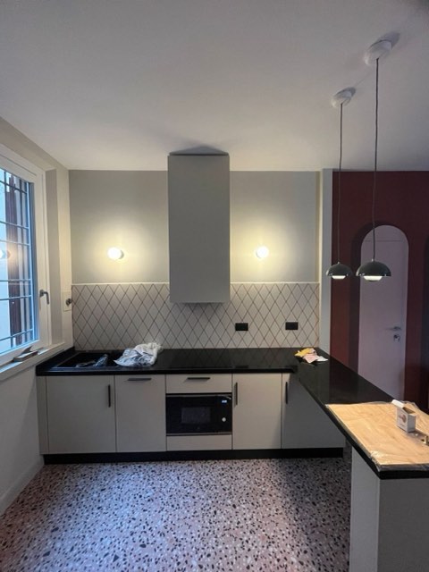 Cucina con applique a parete e sospensioni sulla penisola